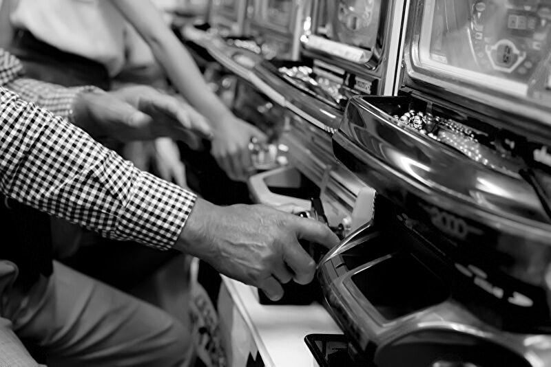 パチンコ台を操作しているプレイヤーの手元を写したイメージ画像。遠隔操作の疑念が生まれる現場の雰囲気を表現